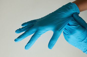 A person wearing blue gloves and holding something in their hand.