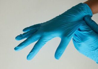 A person wearing blue gloves and holding something in their hand.